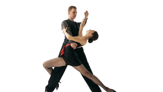 Beautiful sportive young man and woman dancing Argentine tango isolated on white studio background. Artists in black stage costumes. Concept of art, beauty, grace, action, emotions. Copy space for ad