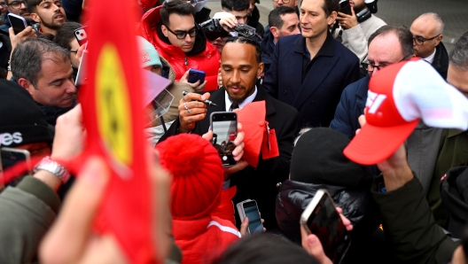 FIORANO MODENESE, ITALY - JANUARY 20: Sir Lewis Hamilton greets fans during his first official days as a Scuderia Ferrari F1 driver at Fiorano Circuit on January 20, 2025 in Fiorano Modenese, Italy. John Elkmann, CEO of Exor, looks on. (Photo by Rudy Carezzevoli/Getty Images)