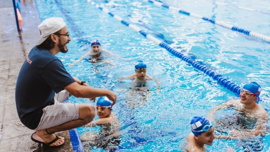 Latin swimming man trainer talking some advices to teenagers swimmers students at the pool in Mexico Latin America