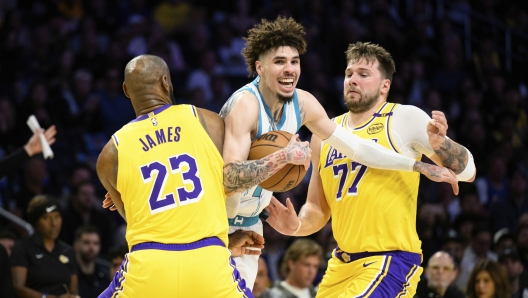 Charlotte Hornets guard LaMelo Ball, center, is contested by Los Angeles Lakers forward LeBron James (23) and Los Angeles Lakers guard Luka Doncic (77) during the first half of an NBA basketball game Wednesday, Feb. 19, 2025, in Los Angeles. (AP Photo/William Liang)