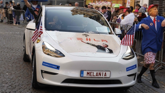 A reveller disguised as US president Donald Trump walks next to a car bearing a picture of Elon Musk's infamous raised-arm salute during the yearly carnival parade in the streets of Aalst, on March 2, 202. (Photo by NICOLAS MAETERLINCK / Belga / AFP) / Belgium OUT