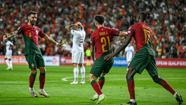 Portugal's forward #21 Diogo Jota celebrates with Portugal's midfielder #8 Bruno Fernandes and Portugal's forward #17 Rafael Leao after scoring a goal during the EURO 2024 first round group J qualifying football match between Portugal and Luxembourg at the Algarve stadium in Almancil, Faro district, on September 11, 2023. (Photo by Patricia DE MELO MOREIRA / AFP)