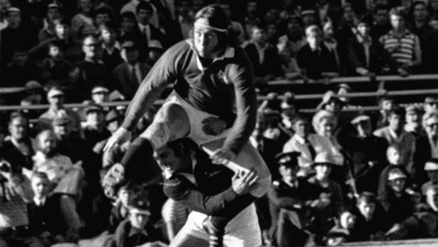 FILE - British Lions winger J.P.R. Williams gets his foot to the ball despite the efforts of Springbok Chris Pope in the test match at Loftus Versfeld, Pretoria, on June 22, 1974. JPR Williams, the Wales rugby great of the 1970s known for his fearlessness and swashbuckling attacking style, has died. He was 74. His death was announced Monday Jan. 8, 2024 by Bridgend Ravens, a club that Williams served as a player and club president. (AP Photo/File)