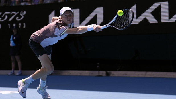 Jannik Sinner of Italy plays a backhand return to Novak Djokovic of Serbia during their semifinal at the Australian Open tennis championships at Melbourne Park, Melbourne, Australia, Friday, Jan. 26, 2024. (AP Photo/Andy Wong)