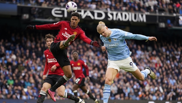Manchester United's Raphael Varane, left, and Manchester City's Erling Haaland challenge for the ball during an English Premier League soccer match between Manchester City and Manchester United at the Etihad Stadium in Manchester, England, Sunday, March 3, 2024. (AP Photo/Dave Thompson)