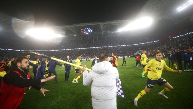 This handout photograph taken and released on March 17, 2024 in Trabzon by Turkish news agency DHA (Demiroren News Agency) shows Fenerbahce's players being attacked by Trabzonspor supporters during the Turkey Super Lig football match between Trabzonspor and Fenerbahce at the Papara Park. (Photo by Handout / DHA (Demiroren News Agency) / AFP) / RESTRICTED TO EDITORIAL USE - MANDATORY CREDIT "AFP PHOTO / DHA (DEMIROREN NEWS AGENCY)" - NO MARKETING NO ADVERTISING CAMPAIGNS - DISTRIBUTED AS A SERVICE TO CLIENTS