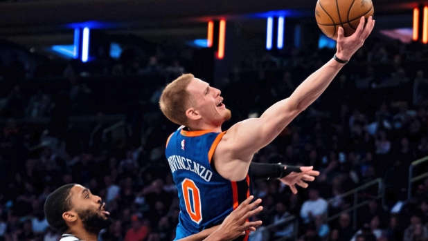 New York Knicks guard Donte DiVincenzo (0) shoots ahead of Brooklyn Nets forward Mikal Bridges during the second half of an NBA basketball game against the Brooklyn Nets in New York, Saturday, March 23, 2024. (AP Photo/Peter K. Afriyie)