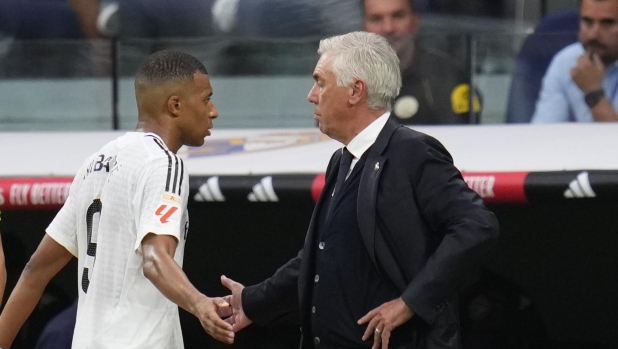 Real Madrid's Kylian Mbappe, centre left, and Real Madrid's head coach Carlo Ancelotti greet each other during a substitution at the Spanish La Liga soccer match between Real Madrid and Valladolid at the Santiago Bernabeu stadium in Madrid, Spain, Sunday, Aug. 25, 2024. (AP Photo/Manu Fernandez)