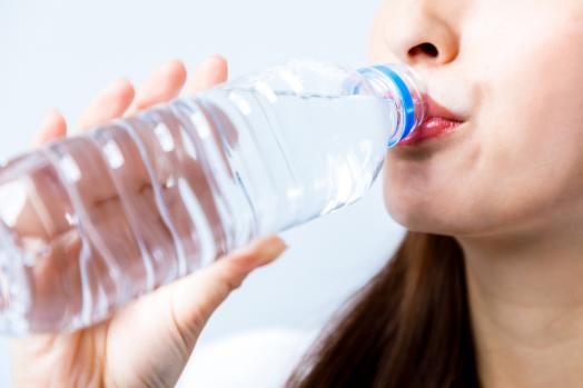 una donna beve dell'acqua da una bottiglia di plastica
