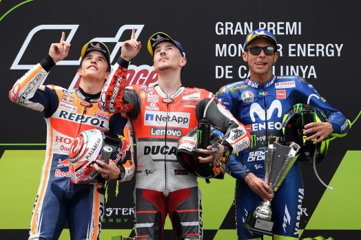 Ducati Team's Spanish rider Jorge Lorenzo (C) celebrates on the podium next to Repsol Honda Team's Spanish rider Marc Marquez (L), second placed, and Movistar Yamaha MotoGP's Italian rider Valentino Rossi (R), third place, after winning the Catalunya MotoGP Grand Prix race at the Catalunya racetrack in Montmelo, near Barcelona on June 17, 2018. / AFP PHOTO / LLUIS GENE