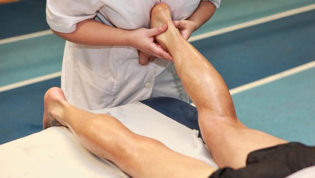 masseuse massaging athlete s Achilles tendon after running