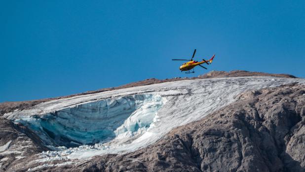 TOPSHOT - A rescue helicopter flies on July 4, 2022 over the glacier that collapsed the day before on the mountain of Marmolada, the highest in the Dolomites, one day after a record-high temperature of 10 degrees Celsius (50 degrees Fahrenheit) was recorded at the glacier's summit. - Rescuers resumed the search for survivors today after an avalanche set off by the collapse of the glacier, the largest in the Italian Alps, killed at least six people and injured eight others. (Photo by Pierre TEYSSOT / AFP)