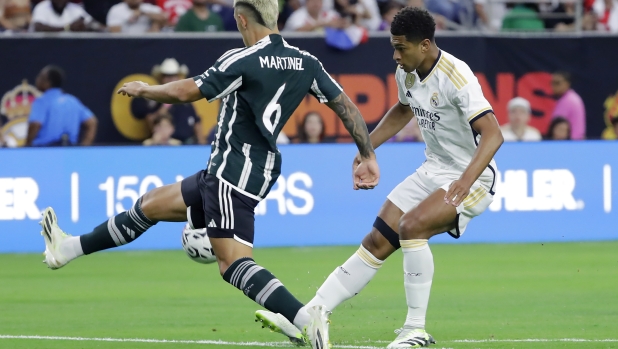 Real Madrid midfielder Jude Bellingham, right, chips the ball over Manchester United defender Lisandro Martinez (6) for a goal during the first half of a Champions Tour friendly soccer match match Wednesday, July 26, 2023, in Houston. (AP Photo/Michael Wyke)