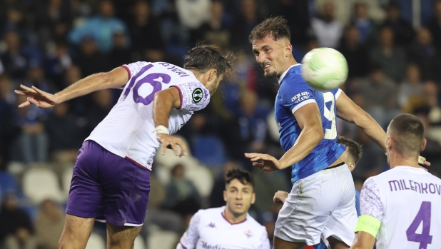 Fiorentina's Luca Ranieri, left, goes up for the ball with Genk's Andi Zeqiri, center, during the Europa Conference League Group F soccer match between KRC Genk and AFC Fiorentina at the Genk Arena in Genk, Belgium, Thursday, Sept. 21, 2023. (AP Photo/Francois Walschaerts)