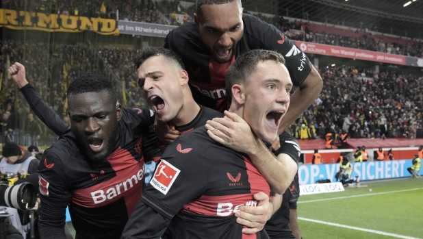 Leverkusen's Florian Wirtz, right, celebrates with teammates Jonathan Tah, up, Victor Boniface, left, and Granit Xhaka, center, after scoring a goal that was seconds later disallowed by a VAR decision during the German Bundesliga soccer match between Bayer Leverkusen and Borussia Dortmund at the BayArena in Leverkusen, Germany, Sunday, Dec. 3, 2023 (AP Photo/Martin Meissner)