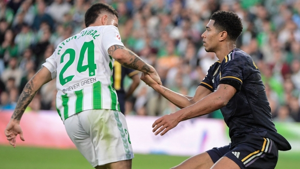 Real Betis' Spanish striker #24 Aitor Ruibal helps Real Madrid's English midfielder #5 Jude Bellingham getting up during the Spanish league football match between Real Betis and Real Madrid CF at the Benito Villamarin stadium in Seville on December 9, 2023. (Photo by CRISTINA QUICLER / AFP)