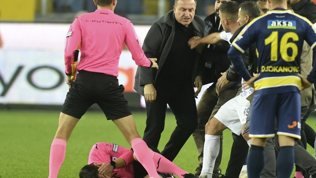 Referee Halil Umut Meler holds his face as he lies on the ground after being punched by MKE Ankaragucu president Faruk Koca, center, at the end of the Turkish Super Lig soccer match between MKE Ankaragucu and Caykur Rizespor in Ankara, Monday, Dec. 11, 2023. The Turkish Football Federation has suspended all league games in the country after a club president punched the referee in the face at the end of a top-flight match. Koca was arrested Tuesday, Dec. 12, 2023, along with two other people on charges of injuring a public official following questioning by prosecutors.  (Abdurrahman Antakyali/Depo Photos via AP)