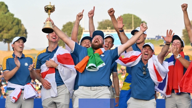 Europe's Irish golfer, Shane Lowry (C) holds The Ryder Cup alongside teammates as they celebrate their victory after the singles matches on the final day of play in the 44th Ryder Cup at the Marco Simone Golf and Country Club in Rome on October 1, 2023. Tommy Fleetwood clinched the crucial half-point as Europe regained the Ryder Cup from a battling United States taking an unassailable lead despite a blistering American singles charge. (Photo by Andreas SOLARO / AFP)