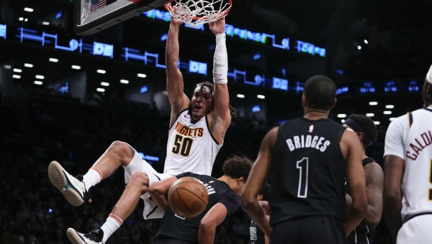 Denver Nuggets' Aaron Gordon (50) dunks the ball in front of Brooklyn Nets' Cameron Johnson and Mikal Bridges (1) during the first half of an NBA basketball game Friday, Dec. 22, 2023, in New York. (AP Photo/Frank Franklin II)