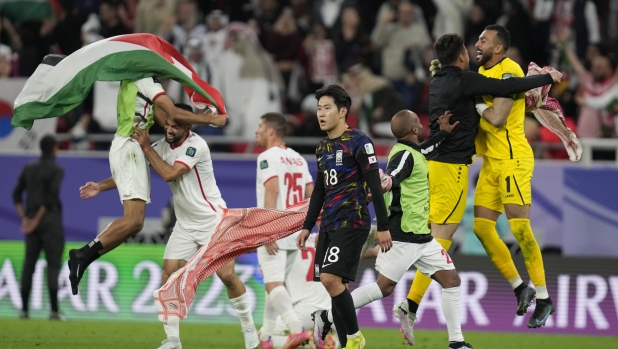 South Korea's Lee Kang-in, centre, reacts as Jordan players celebrates after winning the Asian Cup Semi-finals soccer match between Jordan and South Korea at Ahmad Bin Ali Stadium in Al Rayyan, Qatar, Tuesday, Feb. 6, 2024. (AP Photo/Thanassis Stavrakis)