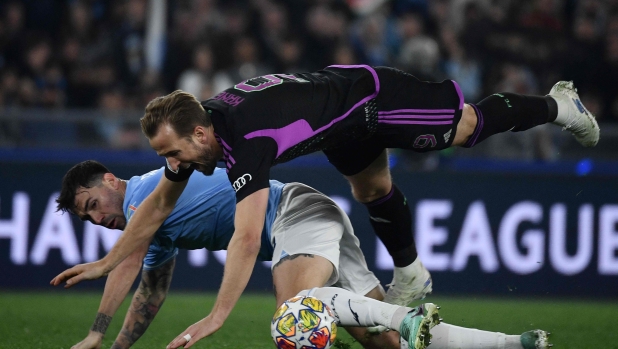 Lazio's Italian defender #13 Alessio Romagnoli (bottom) fights for the ball with Bayern Munich's English forward #09 Harry Kane during the UEFA Champions League last 16 first leg between Lazio and Bayern Munich at the Olympic stadium on February 14, 2024 in Rome. (Photo by Filippo MONTEFORTE / AFP)