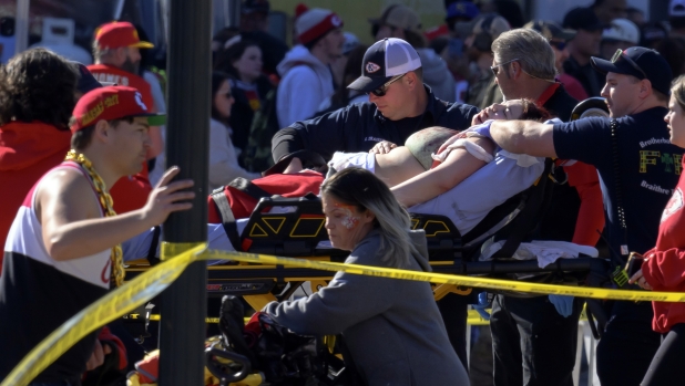 A woman is rushed to an ambulance following a shooting at the Kansas City Chiefs NFL football Super Bowl celebration in Kansas City, Mo., Wednesday, Feb. 14, 2024. Multiple people were injured, a fire official said. (AP Photo/Reed Hoffmann)