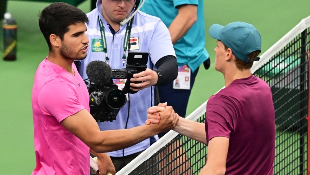 Carlos Alcaraz of Spain (L) meets with Jannik Sinner of Italy at the net following Alcaraz's victory in their semifinal match at the 2023 ATP Indian Wells Open on March 18, 2023 in Indian Wells, California. (Photo by Frederic J. BROWN / AFP)