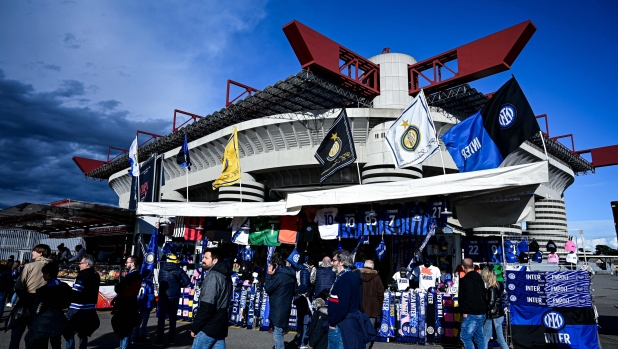 Supporters walk past Inter Milan' scarves, football jerseys and goodies on sale, outside the stadium ahead of the Italian Serie A football match between Inter Milan and Empoli at San Siro Stadium in Milan, on April 1, 2024. (Photo by Piero CRUCIATTI / AFP)
