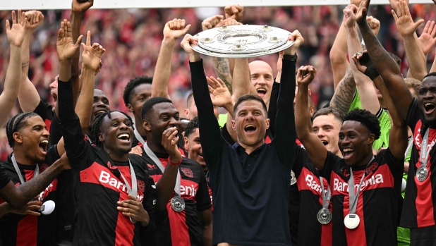 Bayer Leverkusen's Spanish head coach Xabi Alonso and his players celebrate with the Bundesliga trophy after the German first division Bundesliga football match between Bayer 04 Leverkusen and FC Augsburg in Leverkusen, western Germany on May 18, 2024. (Photo by INA FASSBENDER / AFP) / DFL REGULATIONS PROHIBIT ANY USE OF PHOTOGRAPHS AS IMAGE SEQUENCES AND/OR QUASI-VIDEO