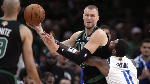 Boston Celtics center Kristaps Porzingis looks to pass while defended by Dallas Mavericks guard Kyrie Irving (11) during the second half of Game 2 of the NBA Finals basketball series, Sunday, June 9, 2024, in Boston. (AP Photo/Steven Senne)