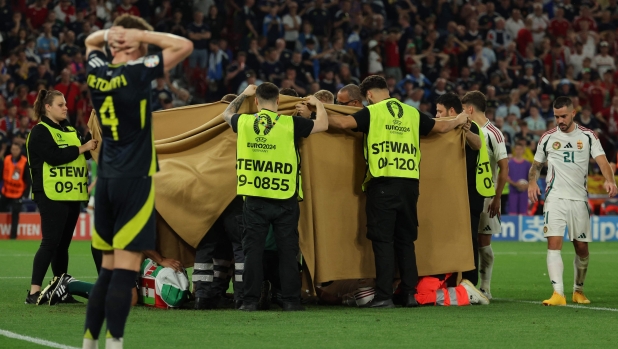 TOPSHOT - Hungary's forward #19 Barnabas Varga, hidden behind a cloth, receives medical treatment during the UEFA Euro 2024 Group A football match between Scotland and Hungary at the Stuttgart Arena in Stuttgart on June 23, 2024. (Photo by LLUIS GENE / AFP)