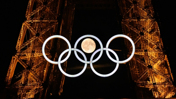 The moon rises behind the Olympic rings displayed on the Eiffel Tower in Paris on July 22, 2024, ahead of the Paris 2024 Olympic Games. (Photo by Loic VENANCE / AFP)