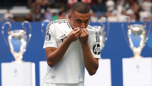 French forward Kylian Mbappe kisses his jersey during a first appearance as a Real Madrid player at the Santiago Bernabeu Stadium in Madrid on July 16, 2024, after signing his new five-season contract. Still celebrating Spain's Euro 2024 triumph, Real Madrid fans have even more to cheer this July 16, 2024, as French superstar Kylian Mbappe is officially presented to a packed-out Santiago Bernabeu stadium. (Photo by Pierre-Philippe MARCOU / AFP)