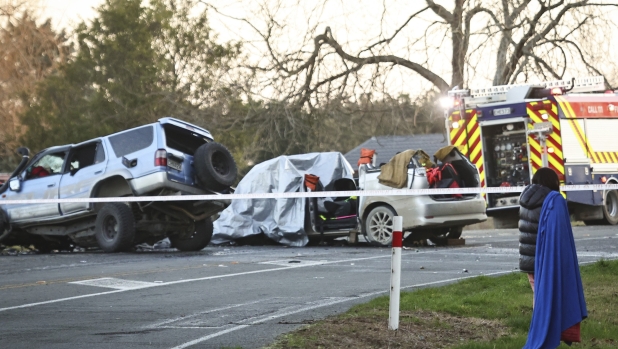 A woman walks past damaged vehicles at a crash site near Geraldine, New Zealand, where South Korean skiers are involved in a fatal accident, Thursday, Aug. 22, 2024. (Aiman Amerul Muner/Timaru Herald/Stuff via AP)