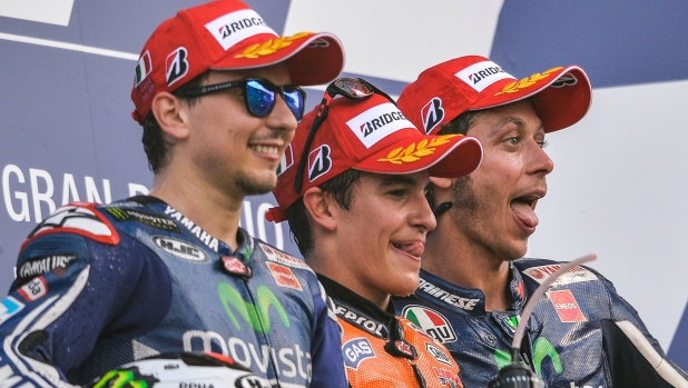 Honda's Spanish rider Marc Marquez (C) celebrates on the podium after winning the Italian Moto Grand Prix at Mugello racetrack on June 1, 2014, flanked by second-placed rider Yamaha's Jorge Lorenzo of Spain (L) and third-placed rider Yamaha's Valentino Rossi of Italy.  AFP PHOTO / ANDREAS SOLARO