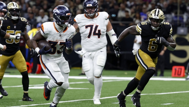 Denver Broncos running back Javonte Williams (33) runs from New Orleans Saints linebacker Willie Gay (6) during an 8-yard touchdown run in the first half of an NFL football game, Thursday, Oct. 17, 2024, in New Orleans. (AP Photo/Butch Dill)