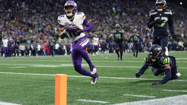 SEATTLE, WASHINGTON - DECEMBER 22: Justin Jefferson #18 of the Minnesota Vikings scores a receiving touchdown past Julian Love #20 of the Seattle Seahawks during the fourth quarter at Lumen Field on December 22, 2024 in Seattle, Washington.   Steph Chambers/Getty Images/AFP (Photo by Steph Chambers / GETTY IMAGES NORTH AMERICA / Getty Images via AFP)