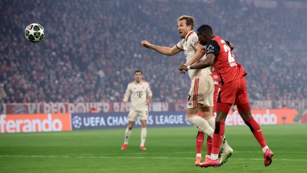 MUNICH, GERMANY - MARCH 05: Harry Kane of Bayern Munich scores his team's first goal past Nordi Mukiele of Bayer 04 Leverkusen during the UEFA Champions League 2024/25 Round of 16 first leg match between FC Bayern Mnchen and Bayer 04 Leverkusen at Allianz Arena on March 05, 2025 in Munich, Germany. (Photo by Alex Grimm/Getty Images)