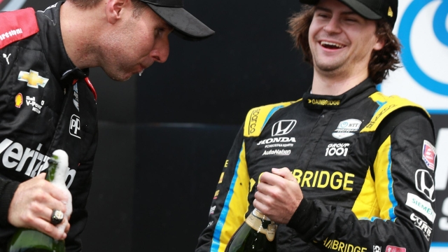INDIANAPOLIS, INDIANA - AUGUST 14: Will Power of Australia, driver of the #12 Verizon 5G Team Penske Chevrolet, (L) celebrates with Colton Herta of the United States, driver of the #26 Gainbridge Andretti Autosport Honda, in victory lane after winning the NTT IndyCar Series Big Machine Spiked Coolers Grand Prix at Indianapolis Motor Speedway on August 14, 2021 in Indianapolis, Indiana.   Sean Gardner/Getty Images/AFP == FOR NEWSPAPERS, INTERNET, TELCOS & TELEVISION USE ONLY ==