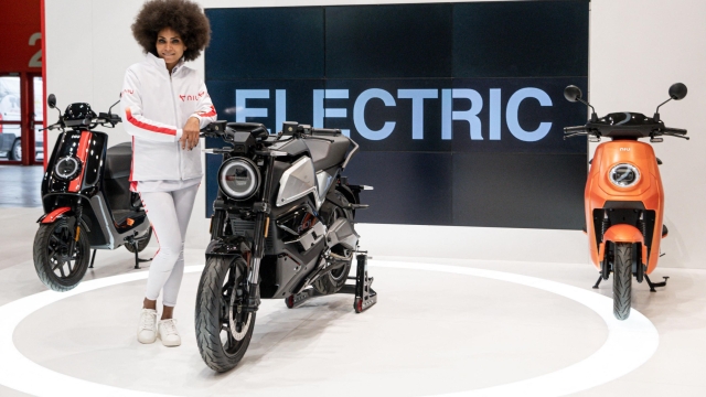 A model poses by motorcycles and motorbikes on display on the NIU stand at EICMA, the 78th edition of the International Bicycle and Motorcycle exhibition during its opening on November 23, 2021 in Milan. (Photo by Piero CRUCIATTI / AFP)