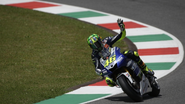 FILE - Italy's Valentino Rossi waves to fans prior to the start of the Italian Moto GP, at the Mugello race circuit, in Scarperia, Italy, on June 2, 2013. Record-breaking motorcycle racer. Charismatic showman. Italy's most popular athlete for years. Valentino Rossi was all that and more. He competed in his final race Sunday at the Valencia Grand Prix. He's the owner of nine world titles that include seven in the premier class. He's considered the greatest modern driver in his sport. (AP Photo/Gregorio Borgia, File)
