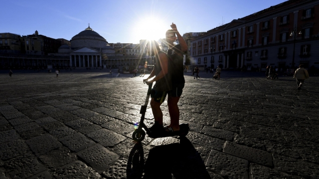 Due ragazzi attraversano in monopattino piazza del Plebiscito a Napoli, 23 settembre 2021. ANSA/CIRO FUSCO