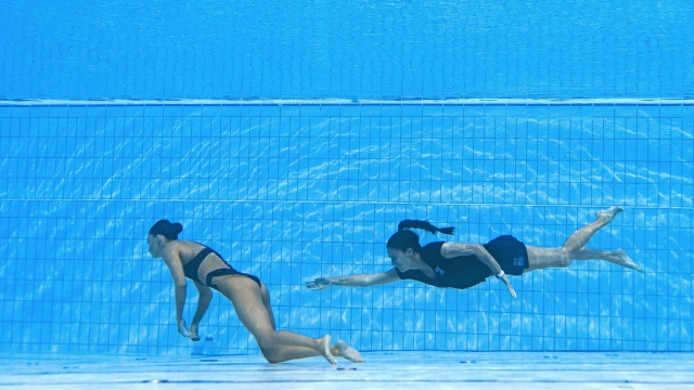 TOPSHOT - A member of Team USA (R) swims to recover USA's Anita Alvarez (L), from the bottom of the pool during an incendent in the women's solo free artistic swimming finals, during the Budapest 2022 World Aquatics Championships at the Alfred Hajos Swimming Complex in Budapest on June 22, 2022. (Photo by Oli SCARFF / AFP)
