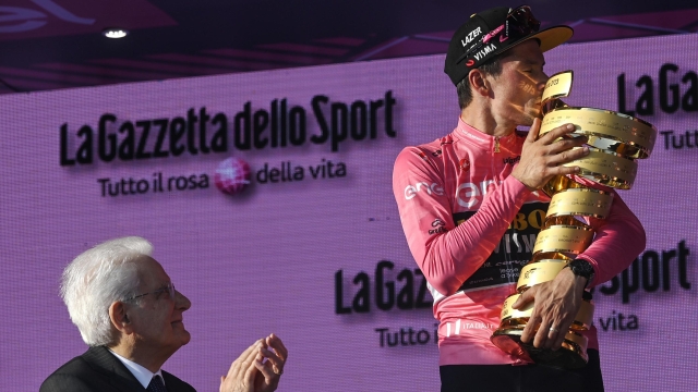 Slovenian rider and winner Primoz Roglic (R), kisses the trophy next to the Italian President of the Republic, Sergio Mattarella (L), after winning the 2023 Giro d'Italia cycling race, Rome, Italy, 28 May 2023. ANSA/RICCARDO ANTIMIANI