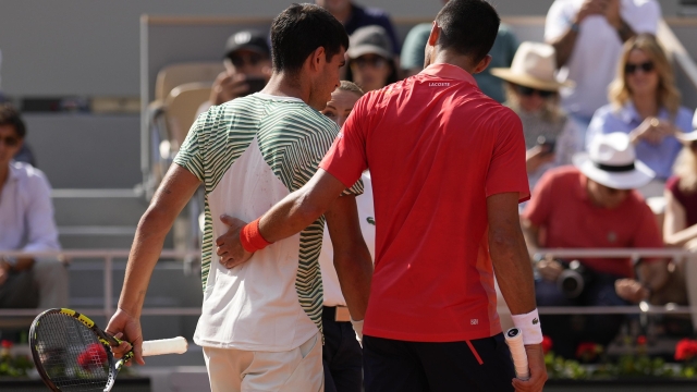 Serbia's Novak Djokovic, right, accompanies Spain's Carlos Alcaraz after he got leg cramps during their semifinal match of the French Open tennis tournament at the Roland Garros stadium in Paris, Friday, June 9, 2023. (AP Photo/Thibault Camus)