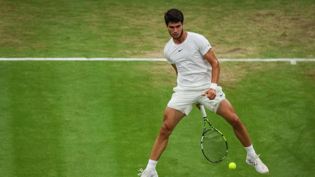 Spain's Carlos Alcaraz returns the ball to Russia's Daniil Medvedev during their men's singles semi-finals tennis match on the twelfth day of the 2023 Wimbledon Championships at The All England Lawn Tennis Club in Wimbledon, southwest London, on July 14, 2023. (Photo by Adrian DENNIS / AFP) / RESTRICTED TO EDITORIAL USE