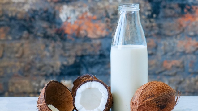 Whole coconuts and coconut products as milk and powder. White stone background.