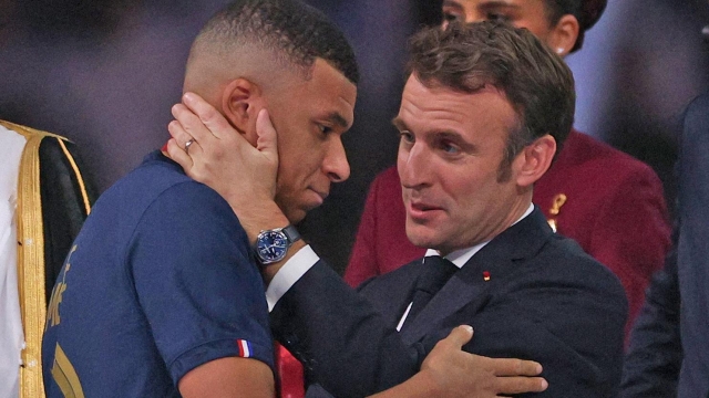 French President Emmanule Macron (R) hands the FIFA Golden Boot award to France's forward #10 Kylian Mbappe (L) during the trophy ceremony at the end of the Qatar 2022 World Cup final football match between Argentina and France at Lusail Stadium in Lusail, north of Doha on December 18, 2022. (Photo by Adrian DENNIS / AFP)