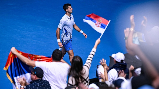 TOPSHOT - Serbia's Novak Djokovic reacts past supporters waving flags of Serbia as he plays against Italy's Jannik Sinner during their men's singles semi-final match on day 13 of the Australian Open tennis tournament in Melbourne on January 26, 2024. (Photo by WILLIAM WEST / AFP) / -- IMAGE RESTRICTED TO EDITORIAL USE - STRICTLY NO COMMERCIAL USE --