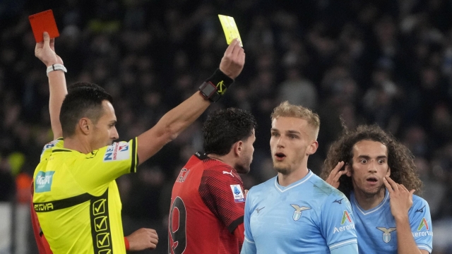 Referee Marco di Bello shows the red card to Lazio's Matteo Guendouzi, background right, and the yellow card to AC Milan's Christian Pulisic during the Italian Serie A soccer match between Lazio and Milan at Rome's Olympic stadium, Friday, March 1, 2024. (AP Photo/Gregorio Borgia)    Associated Press / LaPresse Only italy and Spain